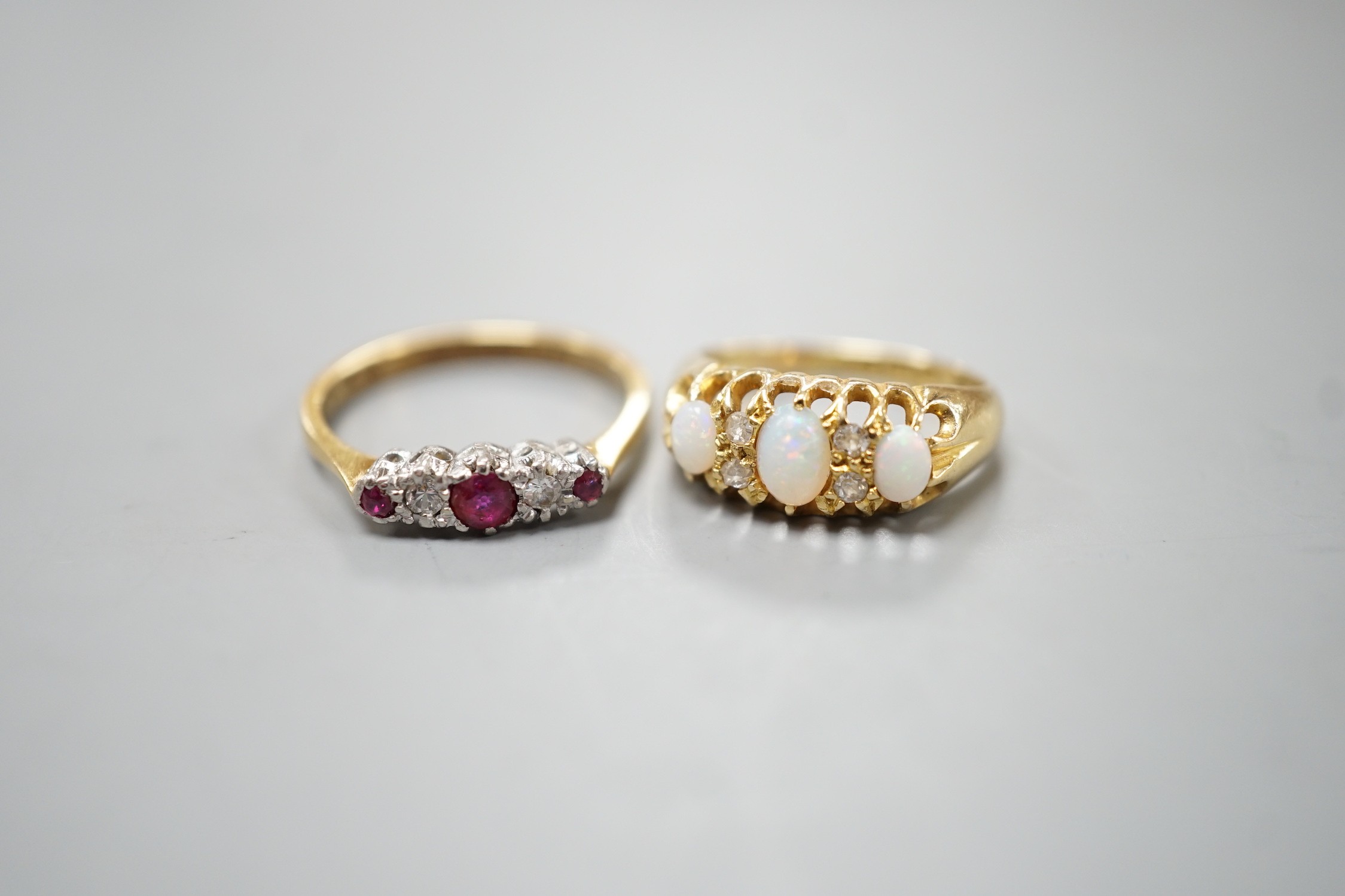 An Edwardian 18ct gold and three stone white opal set ring, with diamond chip spacers, size F and an 18ct and plat, three stone ruby and two stone diamond set ring, size M, gross weight 5.7 grams.
